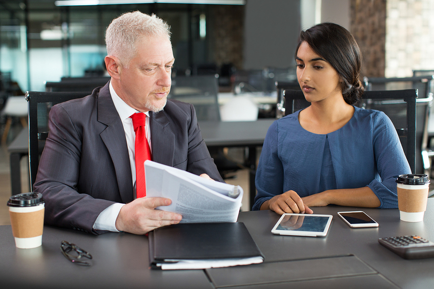 Man referencing a booklet while speaking to a woman.